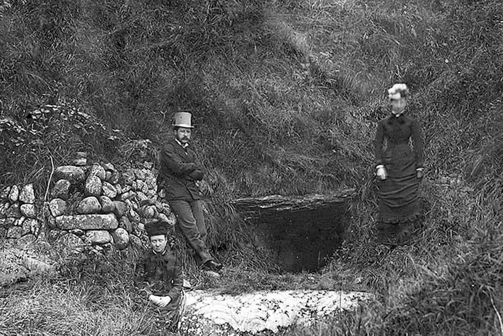 Nineteenth-century photograph of the Newgrange entrance with the carved entrance stone and overgrown mound before modern restoration.